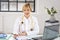 Blond haired female doctor sitting at desk and making notes