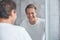 Blond joyous male standing in a bathroom