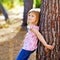 Blond kid girl on autumn tree trunk