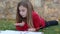Blond kid girl maths homework laying on grass counting with fingers writing
