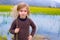 Blond kid girl outdoor holding spike in wetlands lake