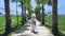 Blond lady walking along palm tree walkway.