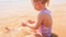 Blond Little Girl Builds Sand Castle on Beach of Azure Sea
