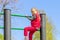 The blond little girl climbed high on the Swedish wall in the park.