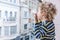 Blond little girl looks at the street from the balcony