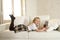 Blond little girl lying on home sofa couch using internet app on digital tablet pad on digital tablet pad