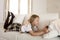 Blond little girl lying on home sofa couch using internet app on digital tablet pad on digital tablet pad