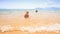 Blond Little Girl Runs with Ball along Sand Beach by Shallow Sea