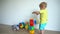 Blond little kid building and destroying tower made of colorful blocks