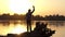 Blond man in earphones dances, raises hands at a sunset in slo-mo