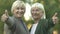 Blond mature women smiling in camera and showing thumbs up, happy pensioners