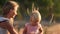 blond mother shows small daughter field flowers in meadow