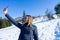 Blond mountaineer woman making a video call with her smart phone, sharing to a friend the achievement of hiking in the snow alone