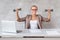 Blond office worker sits in chair behind working desk and holding two dumbbells in hands