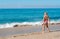 Blond preschool girl wearing colorful swimsuit near the sea on the sand beach