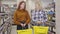 Blond and redhead Caucasian women with shopping baskets posing in wine shop. Joyful young beautiful ladies laughing and