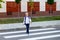 A blond schoolboy with glasses and a backpack goes to school on a pedestrian crosswalk. Day of knowledge