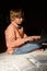 Blond serious boy spending time with notebook, sitting on the floor