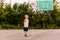 A blond seven-year-old boy in basketball uniform stands on an outdoor basketball court in the summer. Children and sports,