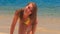 blond slim girl in bikini crawls out of sea approaches camera