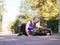 Blond smiling athletic woman in big headphones doing stretching of hamstrings before jogging outdoor in urban park