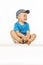 Blond smiling boy sitting on the table wearing baseball cap