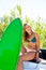 Blond teen surfer girl with green surfboard on car