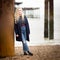 Blond Teenage Girl Leaning Against a Rusty Pier Support