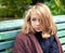 Blond teenage girl in woolen plaid sitting in park