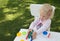Blond toddler girl playing modeling clay in the garden in sunny summer day