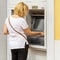 Blond white woman withdraws cash from an ATM