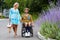 Blond woman in blue dress walking with man in wheelchair along a street