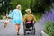 Blond woman in blue dress walking with man in wheelchair along a street