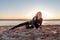 Blond woman fell on the sand dancing on the beach during sunset