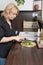 Blond woman is focusing on slicing the cucumber in the modern kitchen