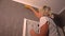 Blond woman hanging wallpaper smoothing it down