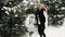 Blond woman has fun, jumps in fir-tree winter forest outdoors