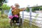 Blond woman hugging man in wheelchair outdoors by  river