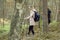 Blond woman making Scandinavian, Nordic walking with backpack, professional sticks or poles in the forest. Joy traveling