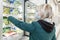 Blond woman in medical mask chooses frozen food in a supermarket. Precautions during the coronavirus pandemic