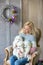 Blond woman posing with husky puppy white color in retro studio shoot on royal armchair. Cute young lady play with puppy dogs in