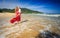 Blond Woman in Red Stands in Surf Clasps Little Girl to Breast