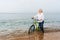 Blond woman wading through the sea with a bike