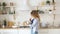 Blond woman whisks in bowl on table by stove in kitchen