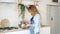 Blond woman whisks in bowl on table by stove in kitchen