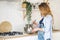 Blond woman whisks in bowl on table by stove in kitchen