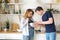 Blond woman whisks food in bowl guy tastes in kitchen