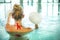 Blond young woman doing aqua aerobics with dumbbells in swimming