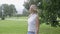 A blond young woman enjoying windy weather in a park.