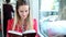 Blond young woman riding tram, reading book